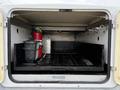 The interior of a service truck compartment featuring a fire extinguisher a metal container and a storage area with grill racks and a bucket