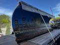 A blue snowplow blade with a mural depicting a cityscape and mountains mounted on a truck bed