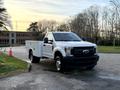 A 2018 Ford F-350 pickup truck with a service body and tool storage compartments on the sides parked on a driveway