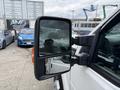 A 2015 Ford F-350 SD with a prominent side mirror reflecting its driver and nearby vehicles