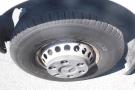 The wheel of a 2012 Mercedes-Benz Sprinter featuring a black tire with visible tread and a silver hubcap with perforations