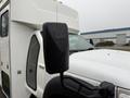 White 2011 Ford F-550 with a prominent side mirror showing raindrops on its surface