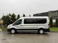 A 2019 Ford Transit van in silver color with black trim and white wheels, parked with its side facing the viewer