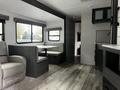 A 2022 Aspen Trail interior featuring a dinette, seating area, and kitchen cabinets with a modern design and neutral color scheme