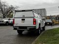 A white 2018 Chevrolet Colorado pickup truck with a bed cover parked at an angle showcasing its rear view and Chevrolet logo