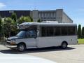 A 2019 Chevrolet Express shuttle bus in gray with large windows parked on a street