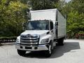 A 2020 Hino 338 truck with a white box cargo area and chrome front grille parked in a driveway
