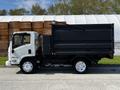 A white 2016 Isuzu NPR truck with a black dump bed parked on a paved surface