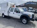 A 2015 Ford F-550 with a white utility body and black accents, featuring dual rear wheels and a front-mounted winch