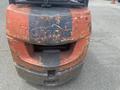 A worn red and blue 2010 Toyota 7FGGU25 forklift with visible scratches and chips on its surface