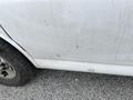 A dirty white 2014 GMC Savana panel showing scratches and marks on the lower side near the tires