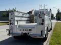 A 2004 Freightliner M2 truck with a large flatbed and hose reels mounted on the back showcasing its utility and cargo capacity