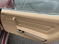 A tan leather door panel of a 1970 Chevrolet Corvette featuring a chrome door handle and a window control switch