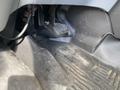 The floor area of a 2019 Ford Transit showing rubber flooring with dirt and debris accumulated in the grooves and a plastic cover near the footwell