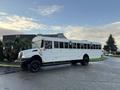 A white 2015 International 3000 school bus parked on a street with large windows and black wheels