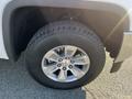 A close-up of the wheel and tire of a 2018 GMC Sierra 1500 showing a silver alloy rim and a rugged black tire with visible tread patterns