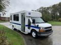 A white 2015 Chevrolet Express with a blue stripe and wheelchair access features a large front windshield and side entry door