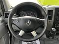 Steering wheel of a 2017 Mercedes-Benz Sprinter featuring controls on the left side and a gear shifter on the right with dashboard instruments visible in the background