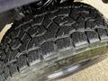 Close-up of a rugged tire with deep tread patterns designed for off-road performance on a 2022 Toyota Tacoma