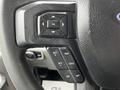 Close-up of the steering wheel controls of a 2017 Ford F-550 featuring buttons for cruise control and audio settings