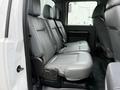 Interior view of the rear seating area of a 2013 Ford F-550 featuring gray leather seats with cup holders and ample legroom