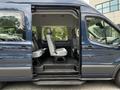A blue 2017 Ford Transit 350 van with the passenger side door open revealing gray seating and an interior designed for multiple passengers