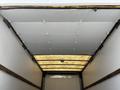 The interior of a 2016 Isuzu NQR truck with a flat ceiling and white panels illuminated by overhead lighting
