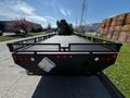 A black 2012 Freightliner M2 112 flatbed truck with a textured metal bed and red taillights facing the viewer