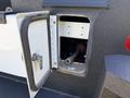 A close-up view of a storage compartment on a 2023 Ford F-550 with an open door revealing a partially visible tool inside