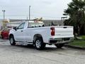 A white 2024 Chevrolet Silverado 1500 pickup truck parked with its rear view facing the camera showcasing the Chevrolet logo and sleek design