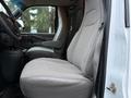 Interior view of a 2016 GMC Savana showing a gray upholstered driver's seat and armrest with a console next to it
