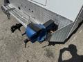 A blue bench vise mounted on a metallic tool holder attached to the rear of a white vehicle