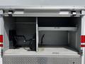A 2009 Ford F-550 with an open storage compartment featuring shelves and brackets but no visible items inside