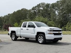 A white 2018 Chevrolet Silverado 1500 pickup truck with four doors and chrome wheels parked at an angle
