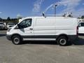 A white 2016 Ford Transit van with a gray lower section and a roof rack visible on top
