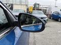A 2021 Kia Forte parked with rain droplets on its side mirror, reflecting the surroundings in a blurred view