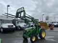 A green 2003 John Deere 790 tractor with a front loader and forks attached, positioned prominently in the foreground