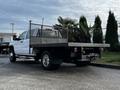 A 2017 GMC Sierra 3500HD pickup truck with a flatbed carrying potted palm trees on the rear