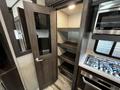 Interior view of a 2021 Grand Design Recreational 311BHS featuring a pantry with shelves and a kitchen area including a stove and oven