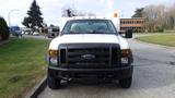 Front view of a 2010 Ford F-550 with a white body block grille and amber lights on the roof