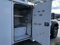 A 2008 Ford F-550 with an open service door revealing a spacious interior with mounted controls and shelves inside