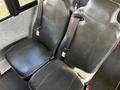Two black leather seats with seatbelts in a bus interior