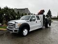 A white 2014 Ford F-550 truck with a flatbed and mounted equipment in the back