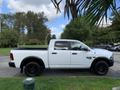 White 2021 RAM 1500 pickup truck with a black bed and black rims parked on a street