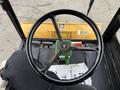 A black steering wheel with a green lever visible in a 1994 John Deere F1145 cab with a yellow snowplow blade attached