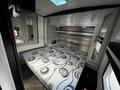 Interior view of a 2022 Heartland Torque showing a bed with a swirling pattern mattress and storage shelves above on a sleek wall with a modern design
