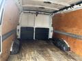 Interior view of a 2022 GMC Savana cargo van showing empty space with wooden paneling on the sides and rubber wheel well covers