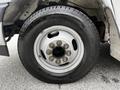 A close-up of a black tire mounted on a silver wheel with multiple lug nut openings and a smooth rubber surface