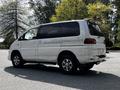 A 2003 Mitsubishi 7 Passenger Van in white with silver accents and chrome wheels parked on a surface