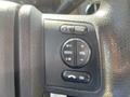 Close-up of a multi-function control panel on a steering wheel with buttons for media, volume, seek, and confirmation on a 2014 Ford F-350 SD